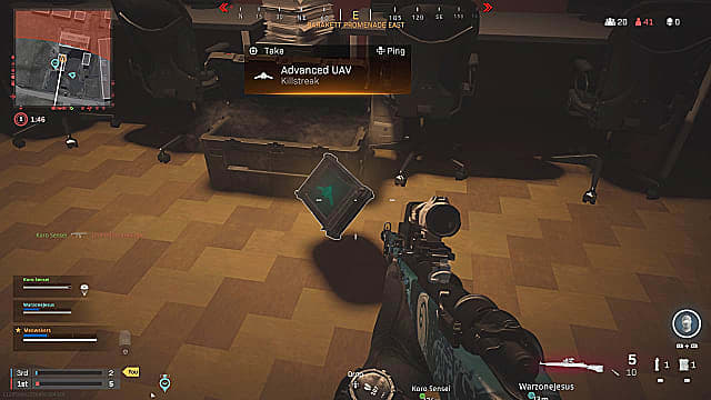 Un joueur tenant un fusil de tireur d'élite, regardant un killstreak avancé d'UAV flottant sur le sol près d'une caisse.