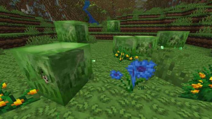 Green slime blocks in a chunk of grass around yellow flowers in Minecraft.