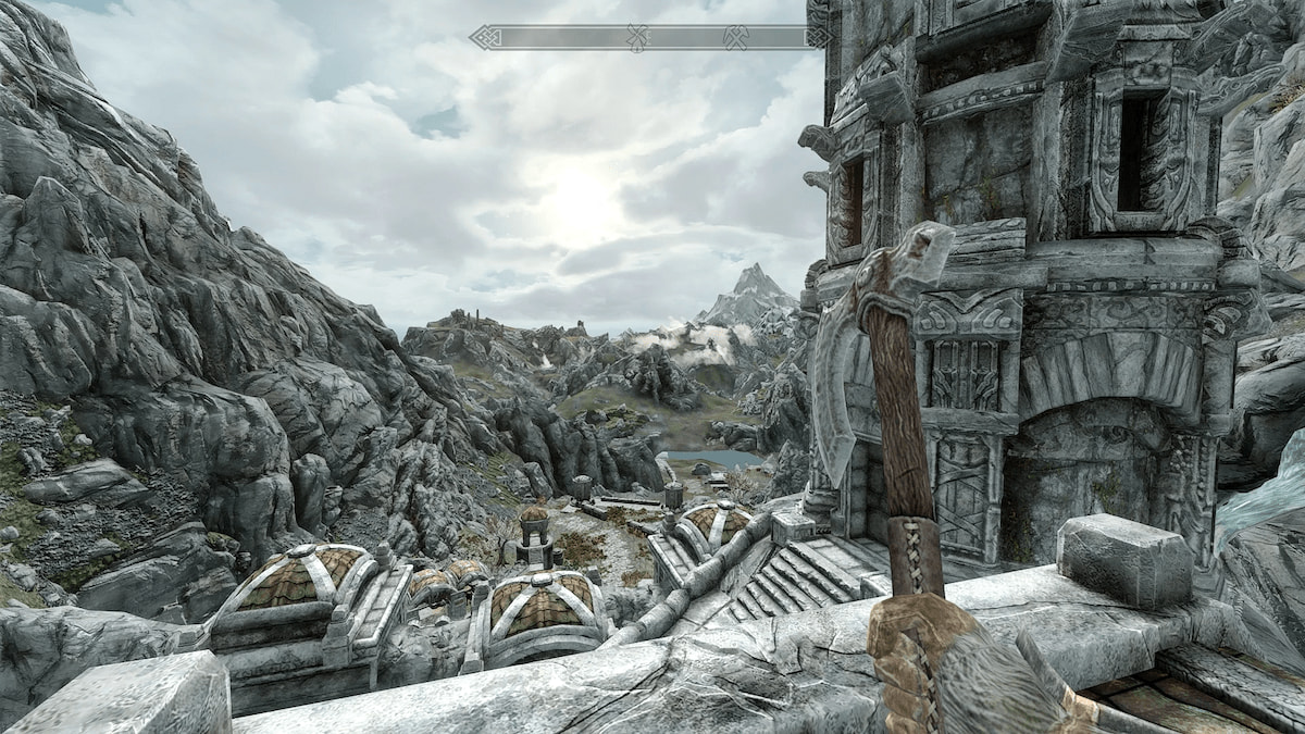 Joueur tenant une hache regardant le paysage de montagne enneigé du haut des ruines